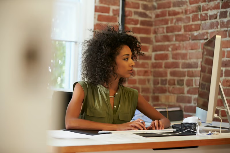 Black woman business owner working at a computer in a modern office, representing entrepreneurship and small business leadership.